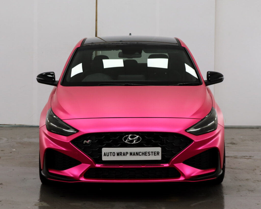 A pink hyundai i30 is parked in a garage.