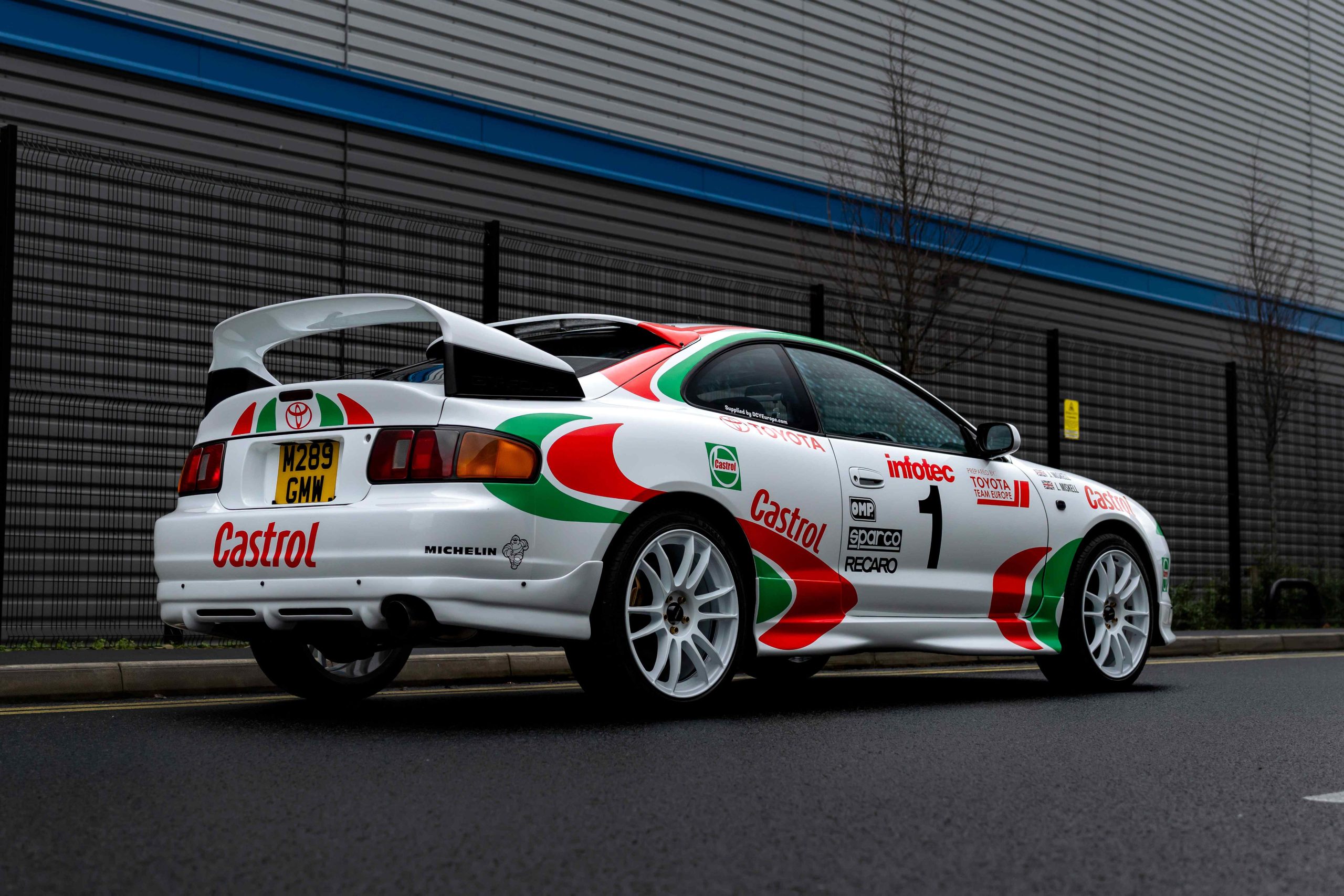A white and green car parked in front of a building.